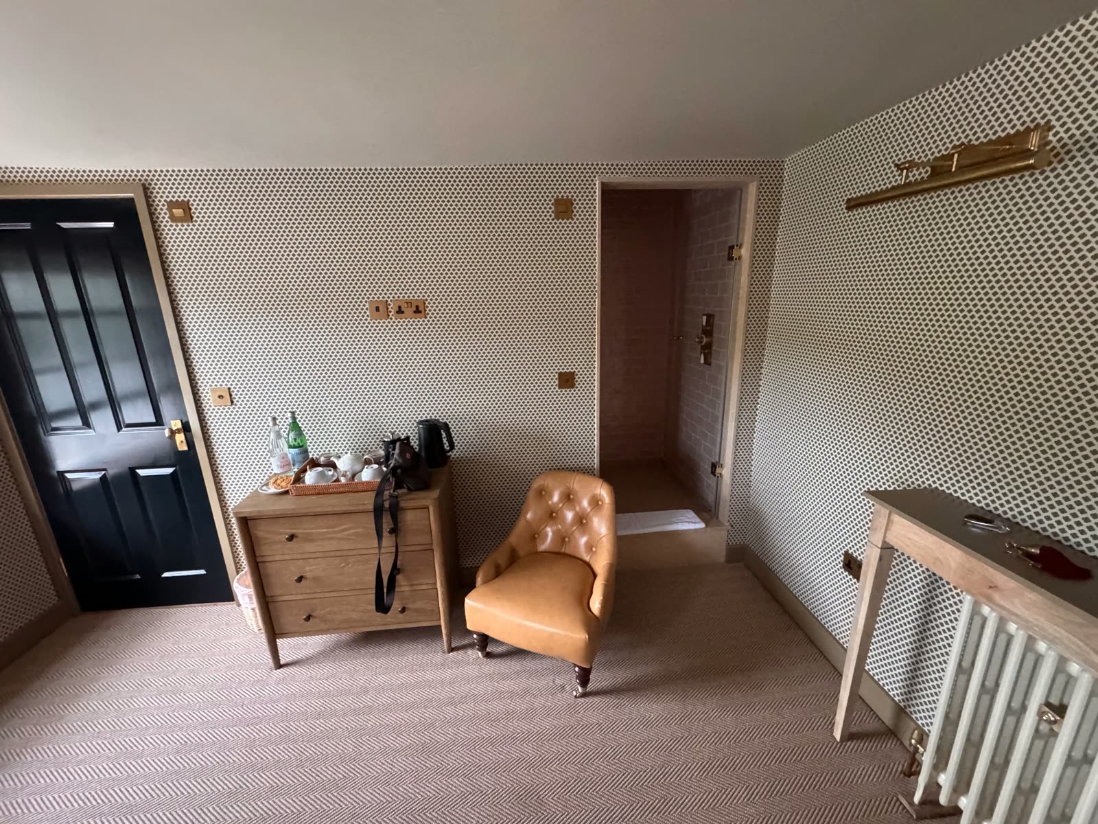 A spacious room at The Norman Knight with a leather chair and walk-in shower